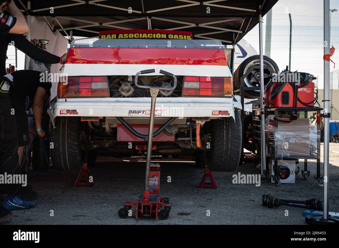 Der BMW E30 in der Box haben Mechaniker das Fahrzeug mit dem Wagenheber angehoben, um die Lager und Achsen zu wechseln Stockfoto