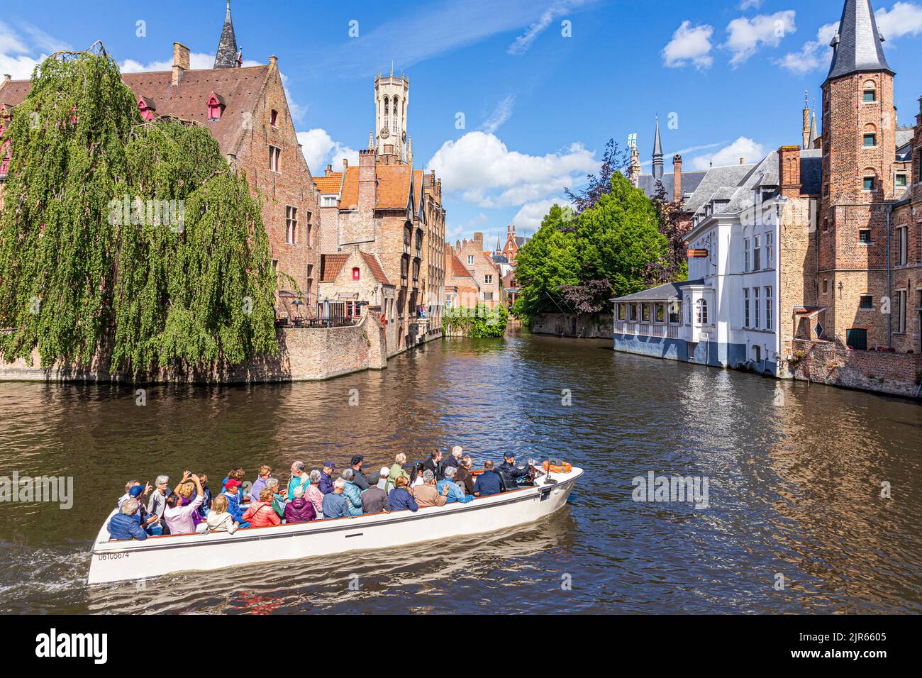 Touristen genießen eine geführte Bootsfahrt um die Kanäle von Brügge, Belgien. Das Duc De Bourgogne Hotel & Restaurant befindet sich im Hintergrund. Stockfoto