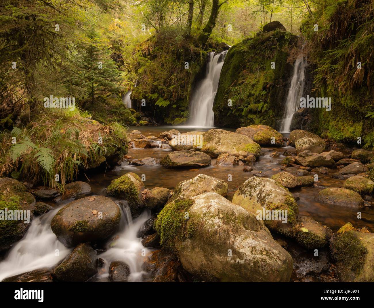 Eine Langzeitaufnahme des Powerscourt Wasserfalls auf moosigen Felsen in Irland Stockfoto