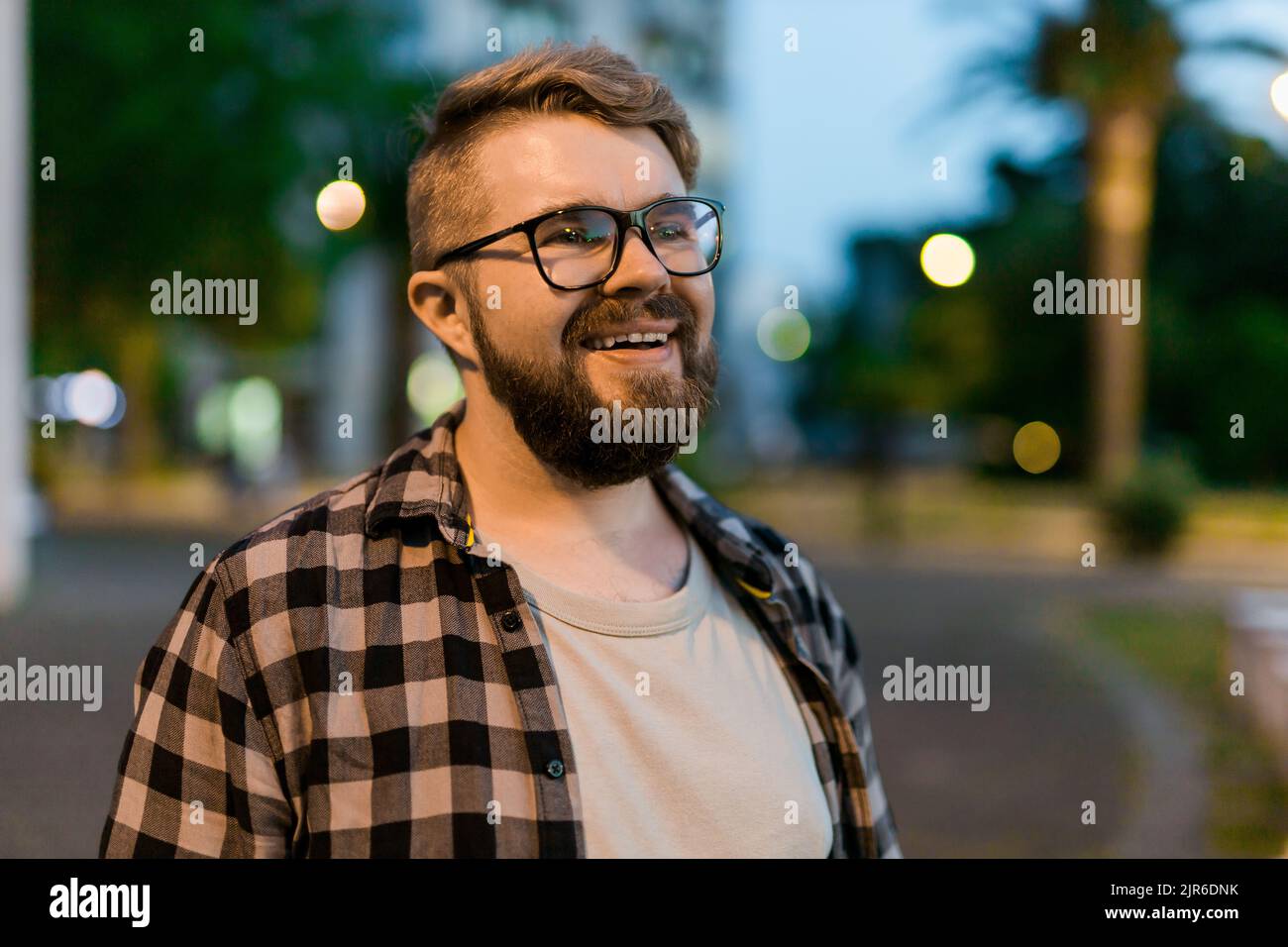 Porträt eines Mannes, der in der Abendstraße der Stadt steht, mit Platz für Text und Kopie. Selbstbewusster, glücklicher Kerl. Nahaufnahme im Hochformat Stockfoto
