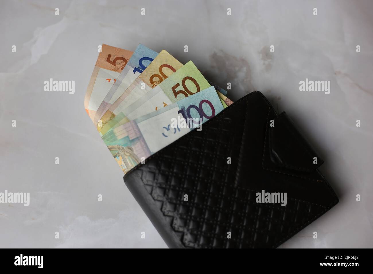 Weißrussische Rubel in einer geschlossenen schwarzen Brieftasche auf grauem Hintergrund Stockfoto