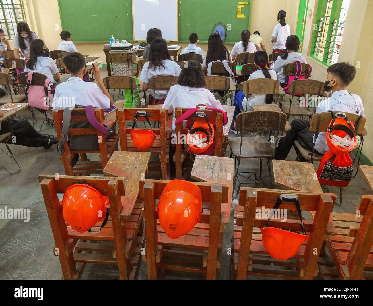 Manila, Philippinen. 22. August 2022. An jedem Schulstuhl der Schüler der Araullo High School in Manila befinden sich Sicherheitshelme. Nach zwei Schuljahren ohne Präsenzunterricht werden die leeren Korridore und Klassenräume wieder voll mit Schülern sein, da das Bildungsministerium (DepEd) am Montag, den 22. August, den Beginn des Schuljahres 2022-2023 offiziell eröffnet. Kredit: SOPA Images Limited/Alamy Live Nachrichten Stockfoto