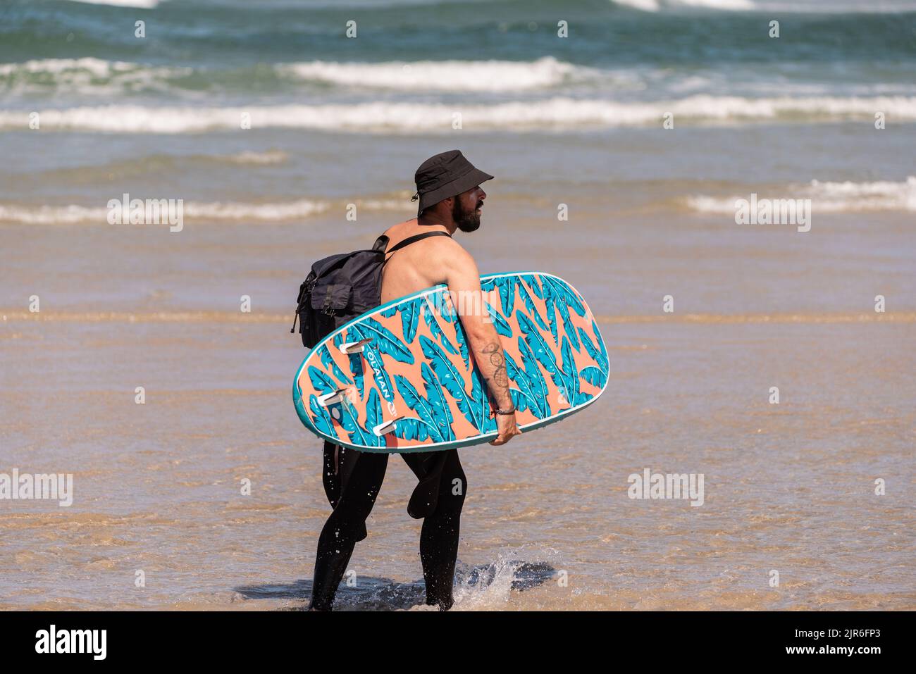 aveiro - portugal. 16. August 2022: Surfkurs am Strand der kaukasische Surfer geht mit seinem Surfbrett ins Meer, um in der Surfklasse Wellen zu fangen. Stockfoto