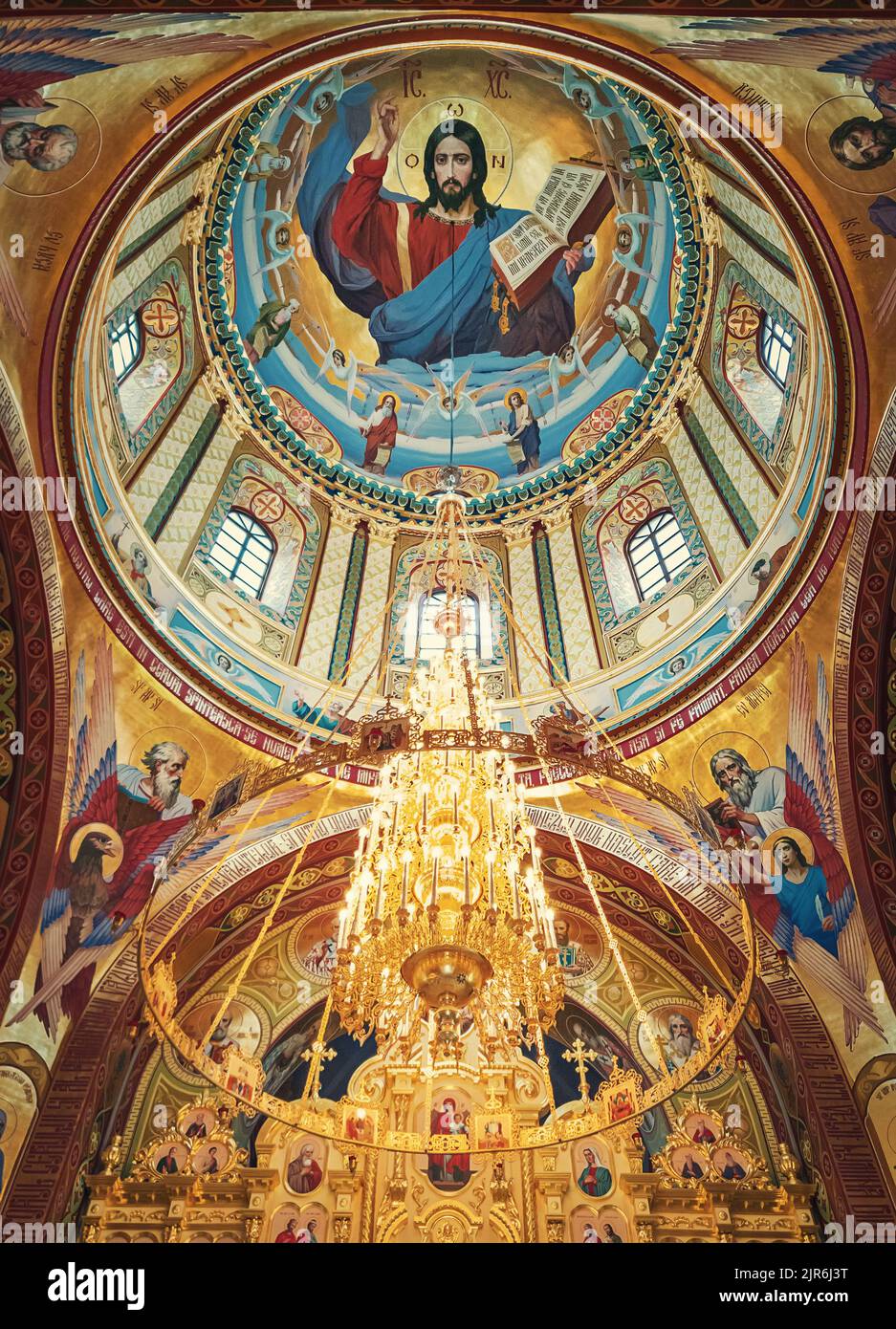 Der Altar mit bemalter Decke des Klosters Curchi, in Orhei, Moldawien. Goldener Kronleuchter mit leuchtenden Lichtern, die an der Kuppel hängen. Verschiedene Heilige i Stockfoto