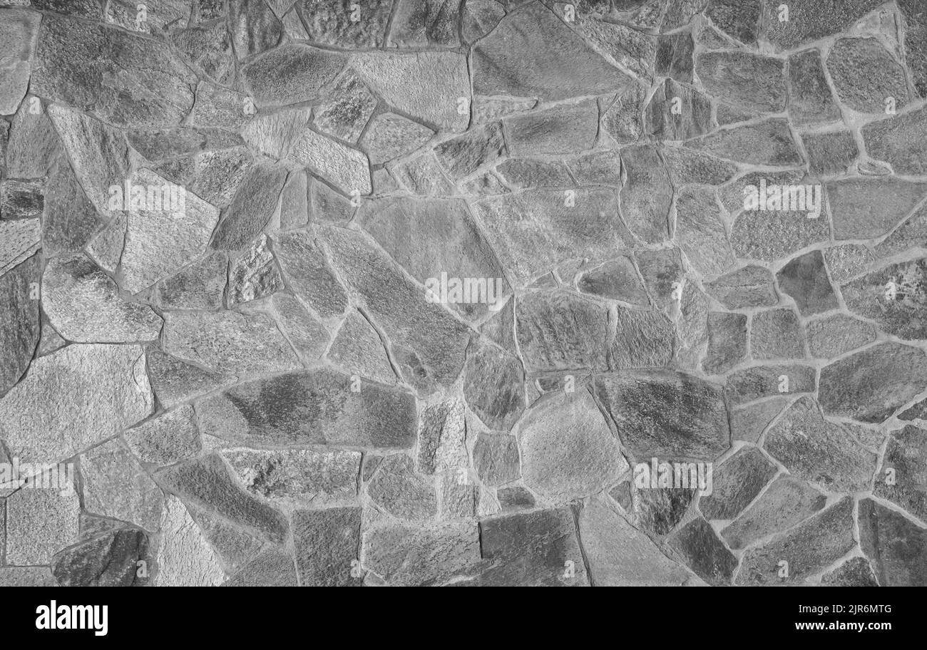 Vorderansicht der Steinwand aus verwitterten Steinschießschatten. Abstrakter, hochauflösender, texturierter Hintergrund im Vollformat in Schwarzweiß. Stockfoto Vorderansicht der Steinwand aus verwitterten Steinschießschatten. Abstrakter, hochauflösender, texturierter Hintergrund im Vollformat in Schwarzweiß. Stockfoto