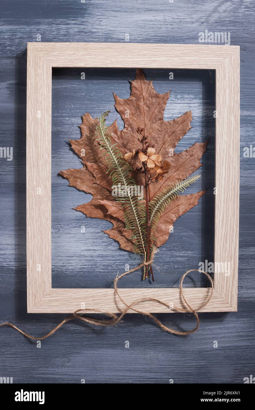 Bouquet aus getrockneten gepressten Blatt in Rahmen auf blauem Hintergrund. Hobby, handgemachte, florale Kunst und boho Stil Konzept. Stockfoto