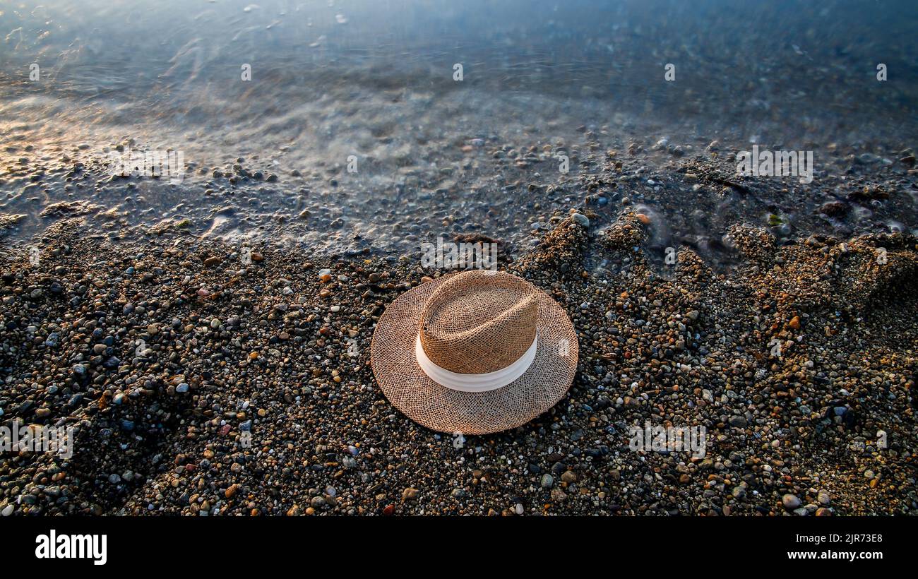 Strohhut am Strand neben dem Wasserrand von oben mit Kopierplatz Stockfoto