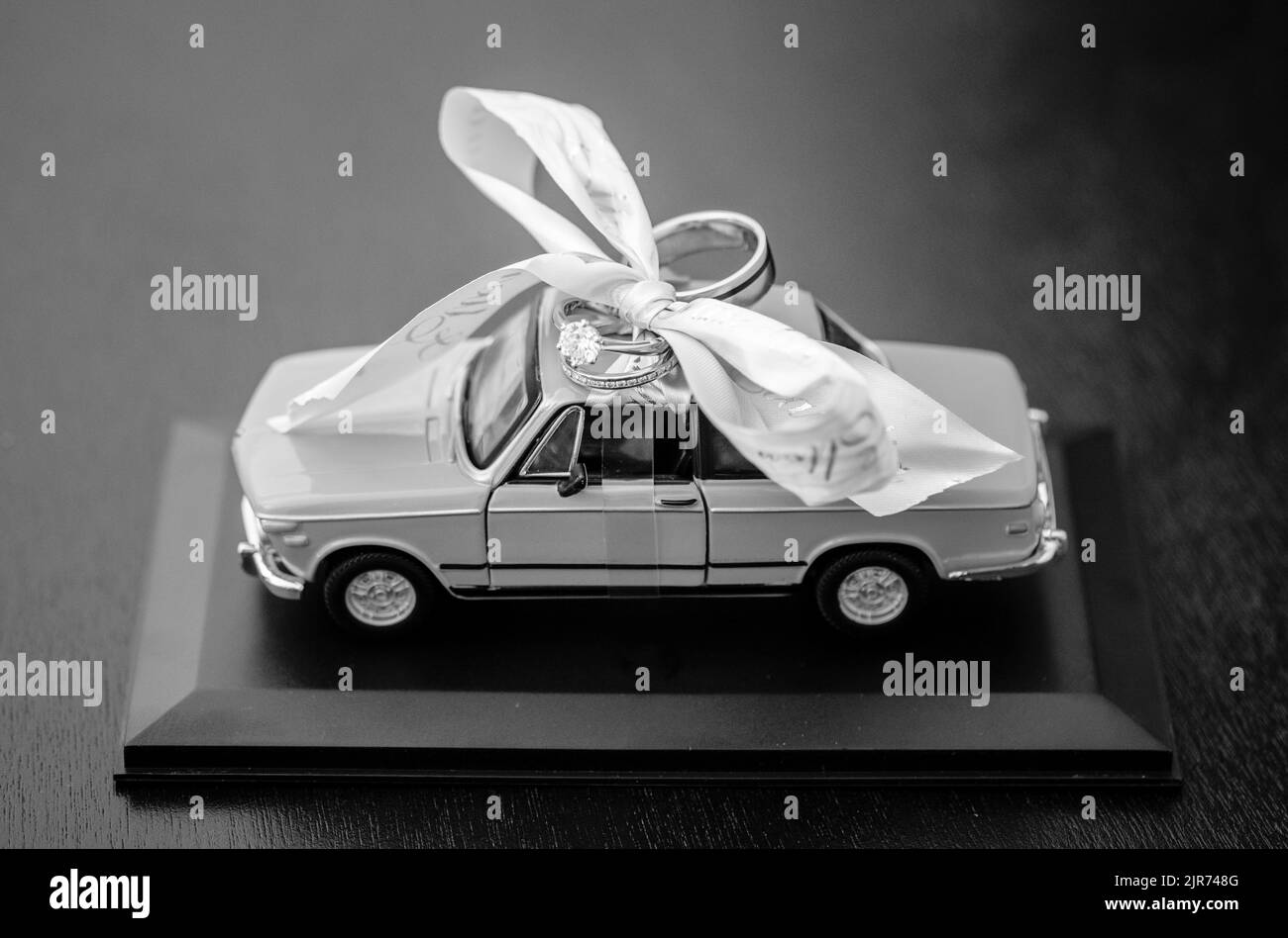 Eine Graustufenaufnahme einer Mini-Autodekoration mit Ringen für eine Hochzeitszeremonie Stockfoto