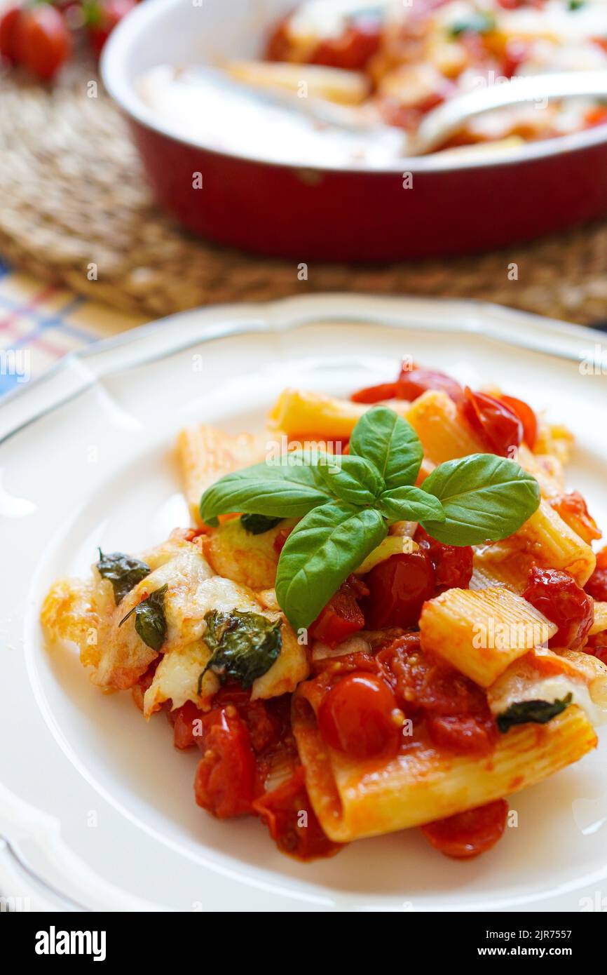 Italienische Paccheri-Pasta mit Kirschtomatensoße, Mozzarella-Käse und frischem Basilikum Stockfoto