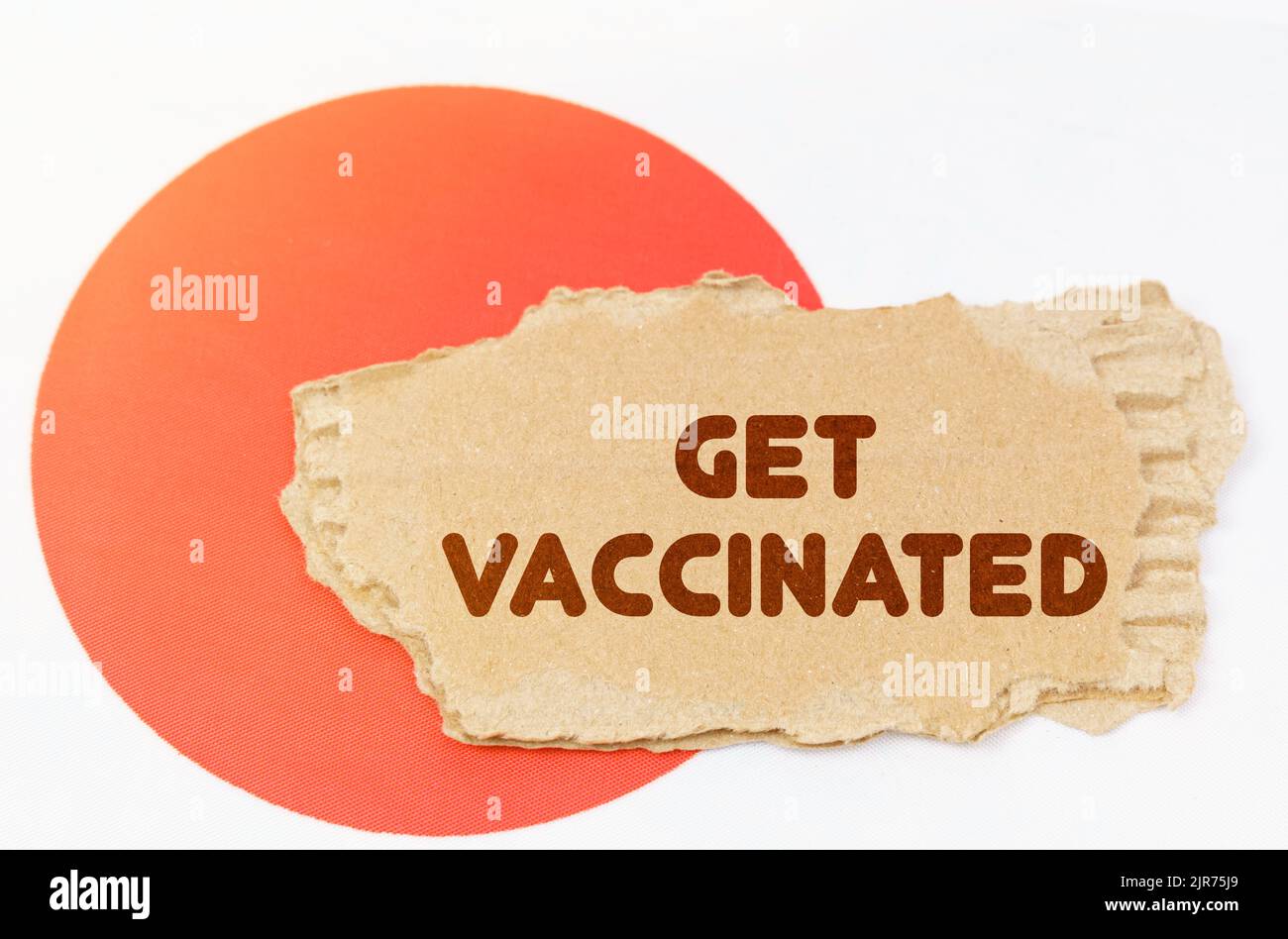 Konzept der nationalen Medizin. Auf der Flagge Japans liegt ein Notizbuch mit der Aufschrift - get impften Stockfoto