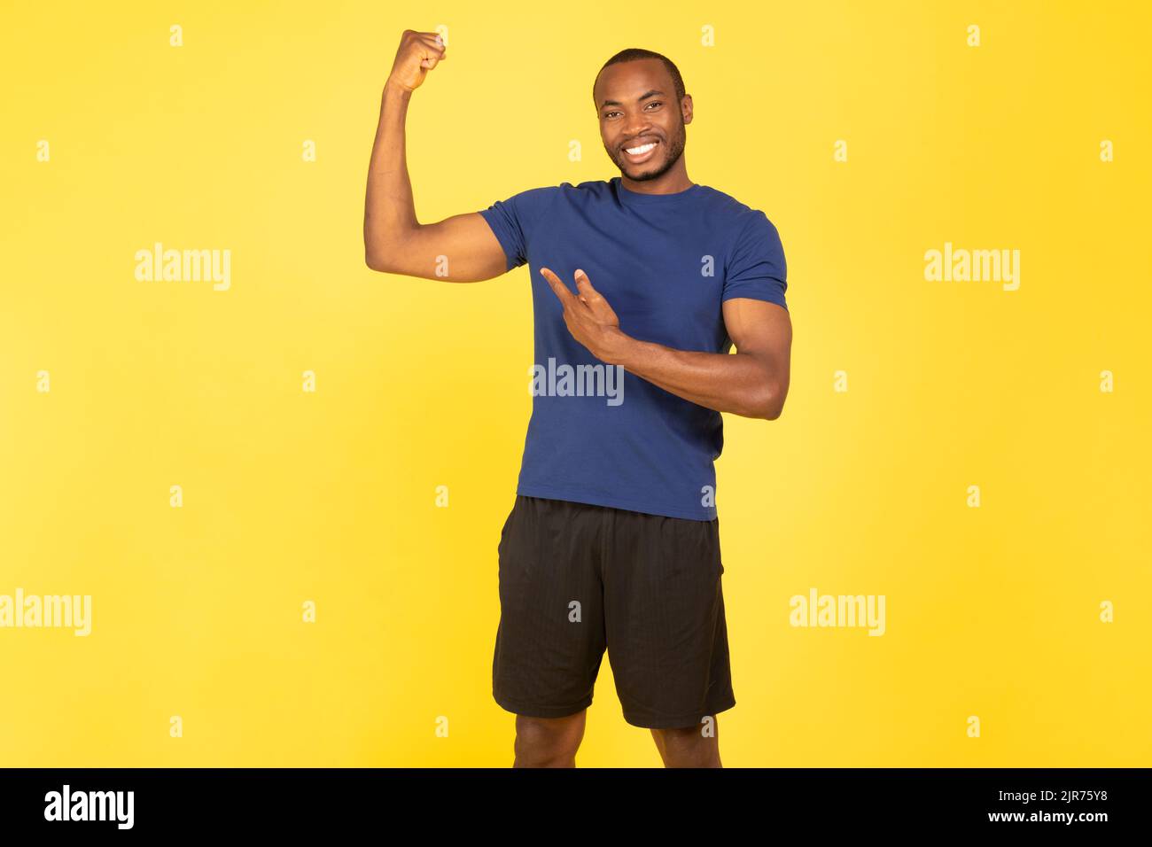 Happy Black Sportsman Zeigt Biceps Muskeln Posiert Über Gelben Hintergrund Stockfoto