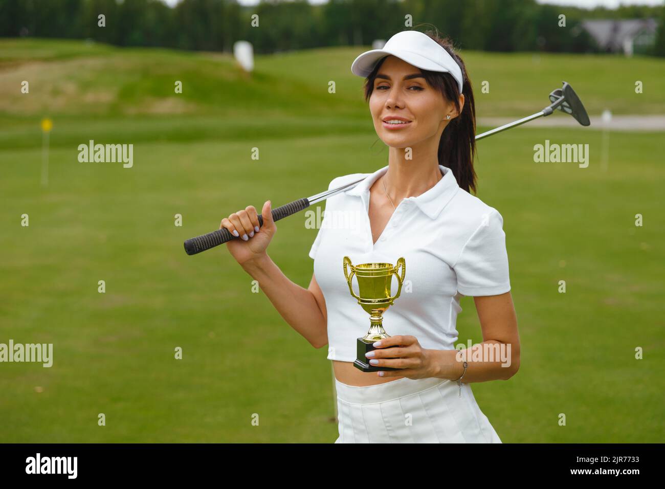 Glückliche Golferin Frau Porträt hält die goldene Tasse des Gewinners im Freien Stockfoto