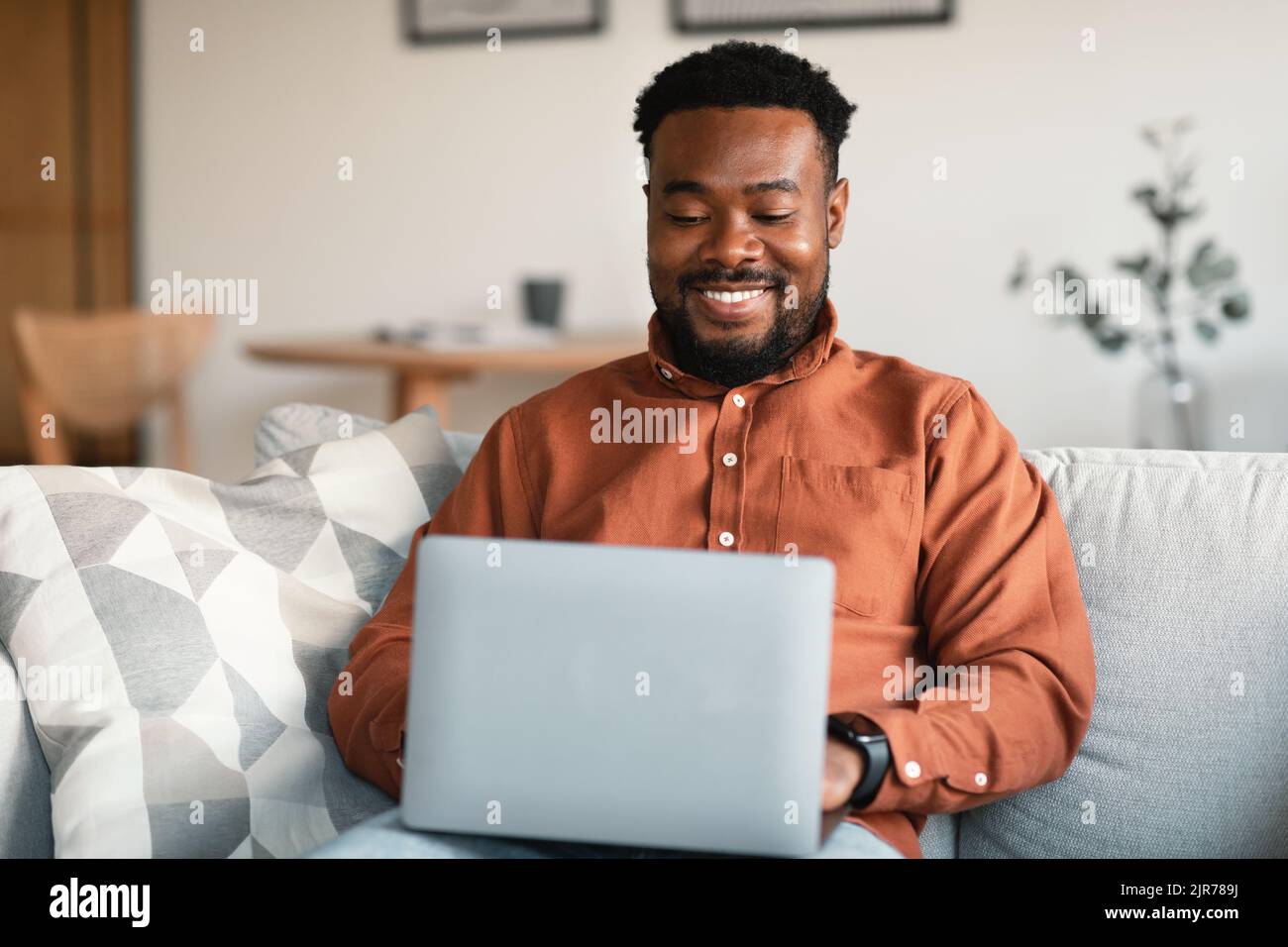 Schwarzer Männlicher Unternehmer, Der Laptop-Surfen Verwendet, Der Online Zu Hause Arbeitet Stockfoto