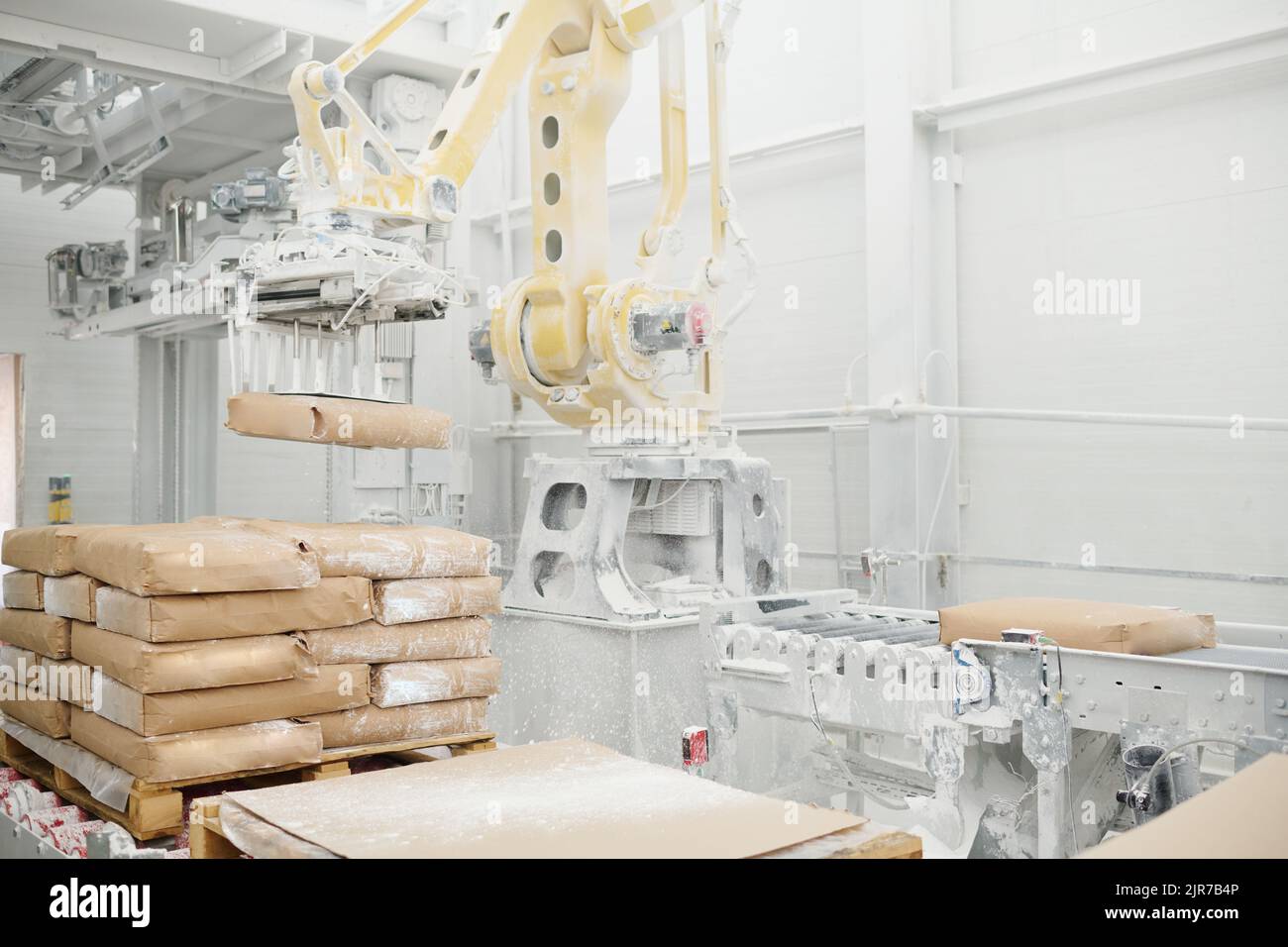 Riesige hydraulische industrielle Maschine, die schwere Pakete hebt und sie auf Produktionslinie in der Werkstatt der modernen Fabrik setzt Stockfoto