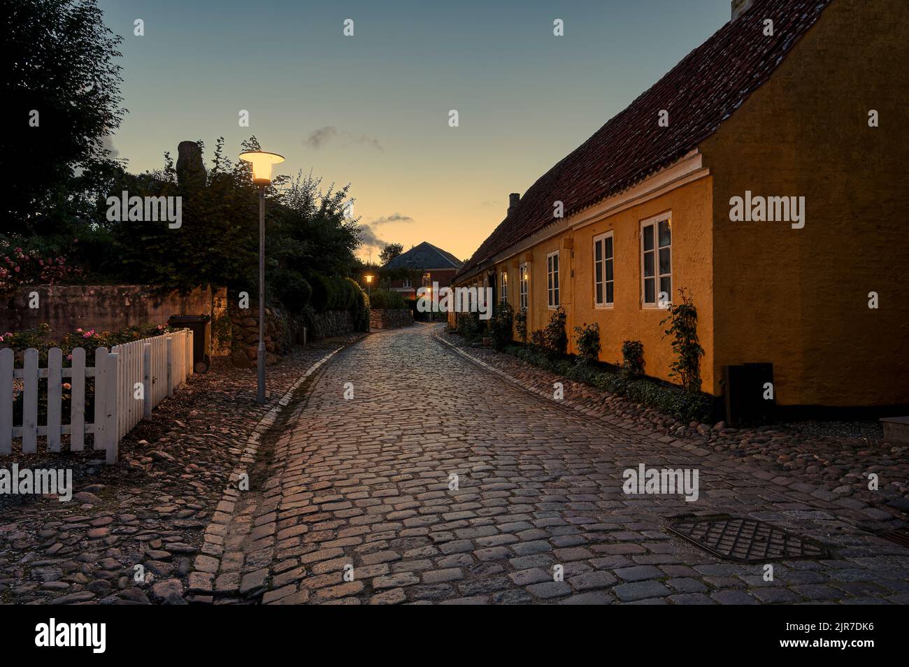 Gelbes Haus an einer Gasse, die in der Dämmerung von einer Straßenlaterne beleuchtet wird, Mariager, Dänemark, 6. August 2022 Stockfoto