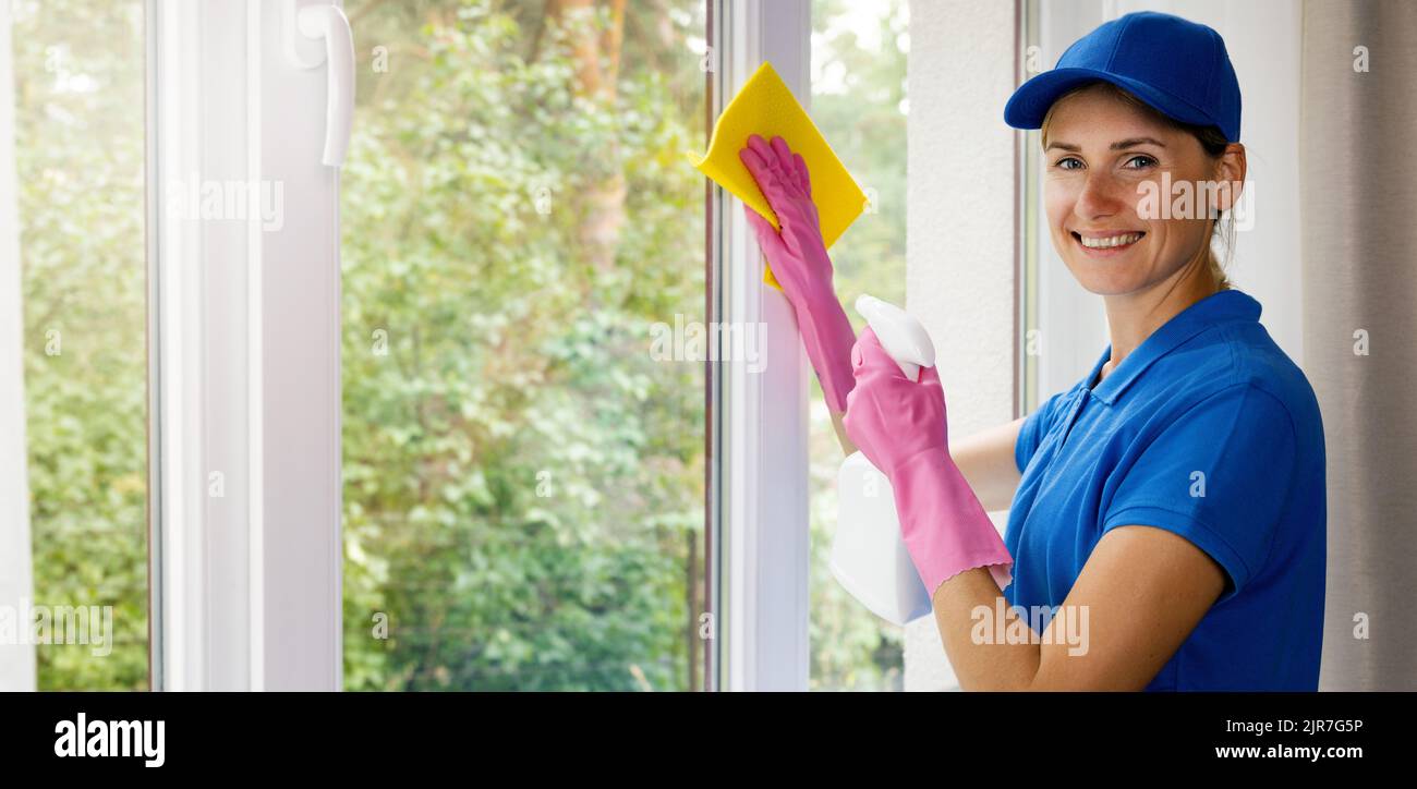 Lächelnde Frau Hausmeister in blauer Uniform reinigen ein Haus. Reinigungsdienste. Banner mit Kopierraum Stockfoto