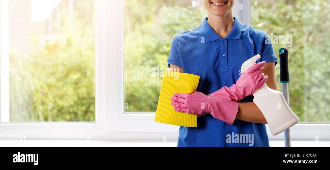 Hausreinigungsservice - lächelnde weibliche Reinigungskraft, die mit Tuch und Waschmittel in den Händen steht. Banner mit Kopierraum Stockfoto
