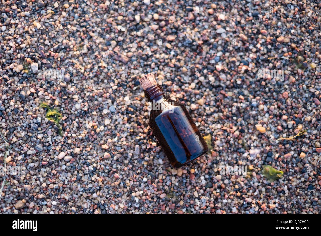 Flasche ätherisches Öl an einem Strand mit Felsen. Kleine braune Medizinflasche im Hintergrund der Natur. Hanföl aus biologischem CBD. Stockfoto