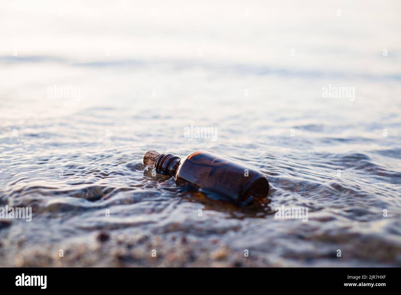 Flasche ätherisches Öl am Strand in Wellen. Kleine braune Medizinflasche im Hintergrund der Natur. Hanföl aus biologischem CBD. Stockfoto