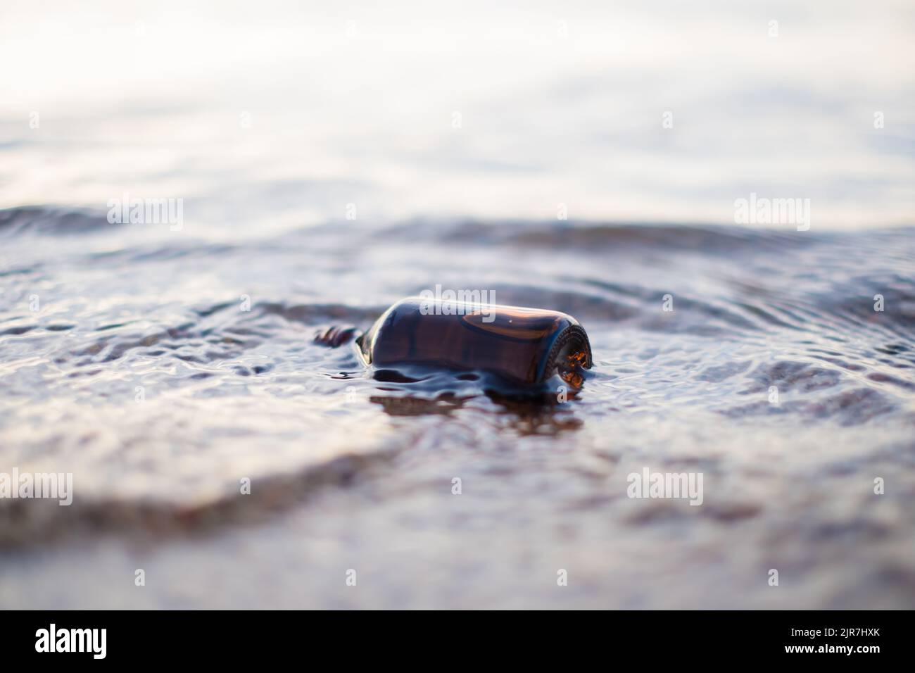 Flasche ätherisches Öl am Strand in Wellen. Kleine braune Medizinflasche im Hintergrund der Natur. Hanföl aus biologischem CBD. Stockfoto