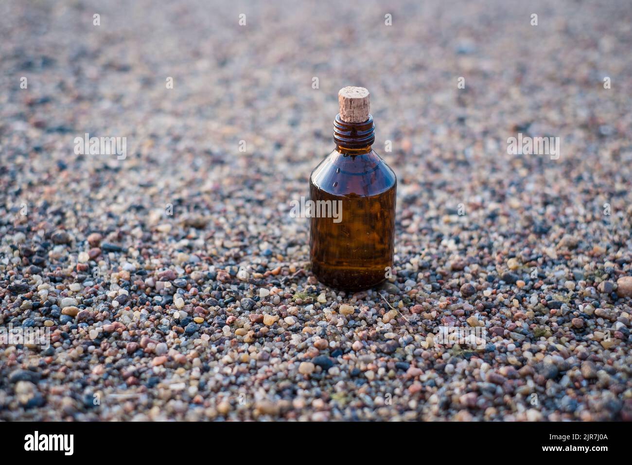 Flasche ätherisches Öl an einem Strand mit Felsen. Kleine braune Medizinflasche im Hintergrund der Natur. Hanföl aus biologischem CBD. Stockfoto