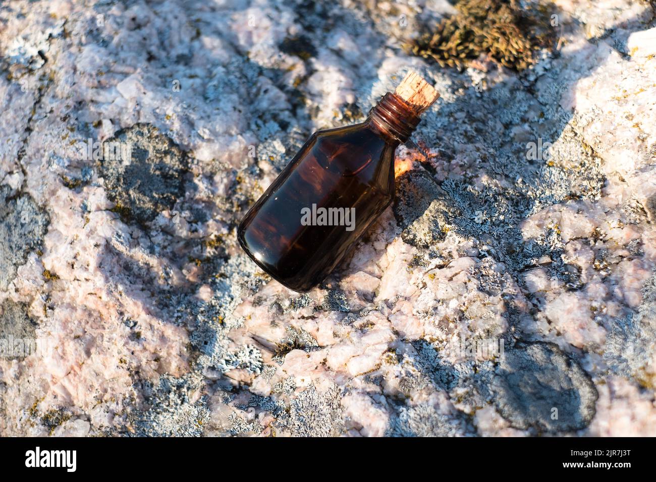 Flasche mit ätherischem Öl auf einem Felsen. Kleine braune Medizinflasche im Hintergrund der Natur. Hanföl aus biologischem CBD. Stockfoto