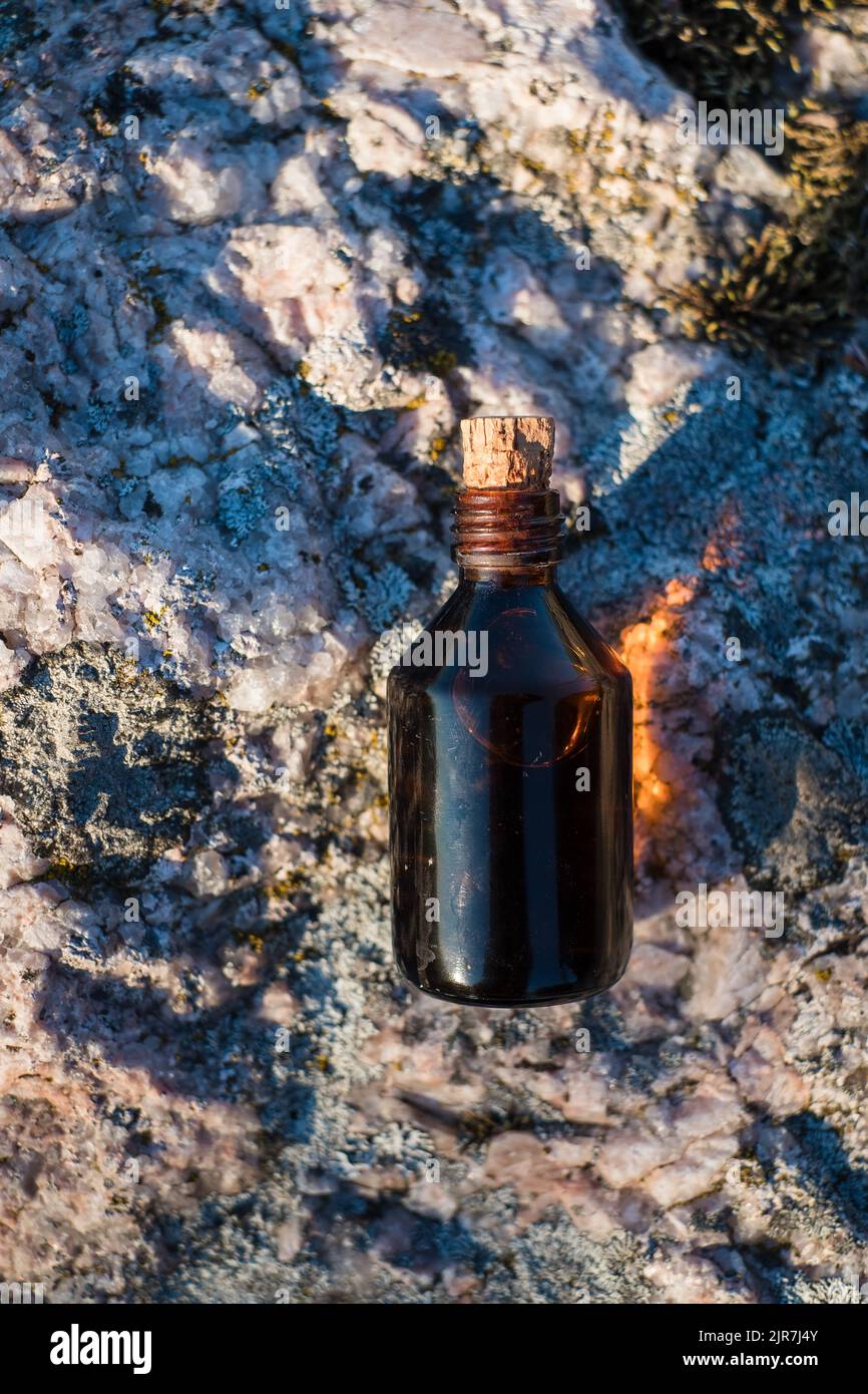 Flasche mit ätherischem Öl auf einem Felsen. Kleine braune Medizinflasche im Hintergrund der Natur. Hanföl aus biologischem CBD. Stockfoto