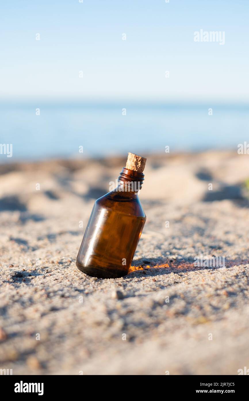 Flasche ätherisches Öl an einem Sandstrand. Kleine braune Medizinflasche im Hintergrund der Natur. Hanföl aus biologischem CBD. Stockfoto