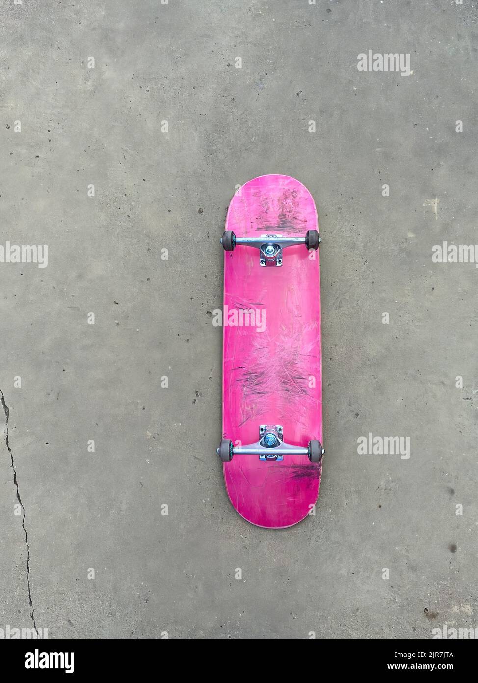 Rosafarbenes Skateboard, das auf einer glatten Betonoberfläche im lokalen Skatepark liegt Stockfoto