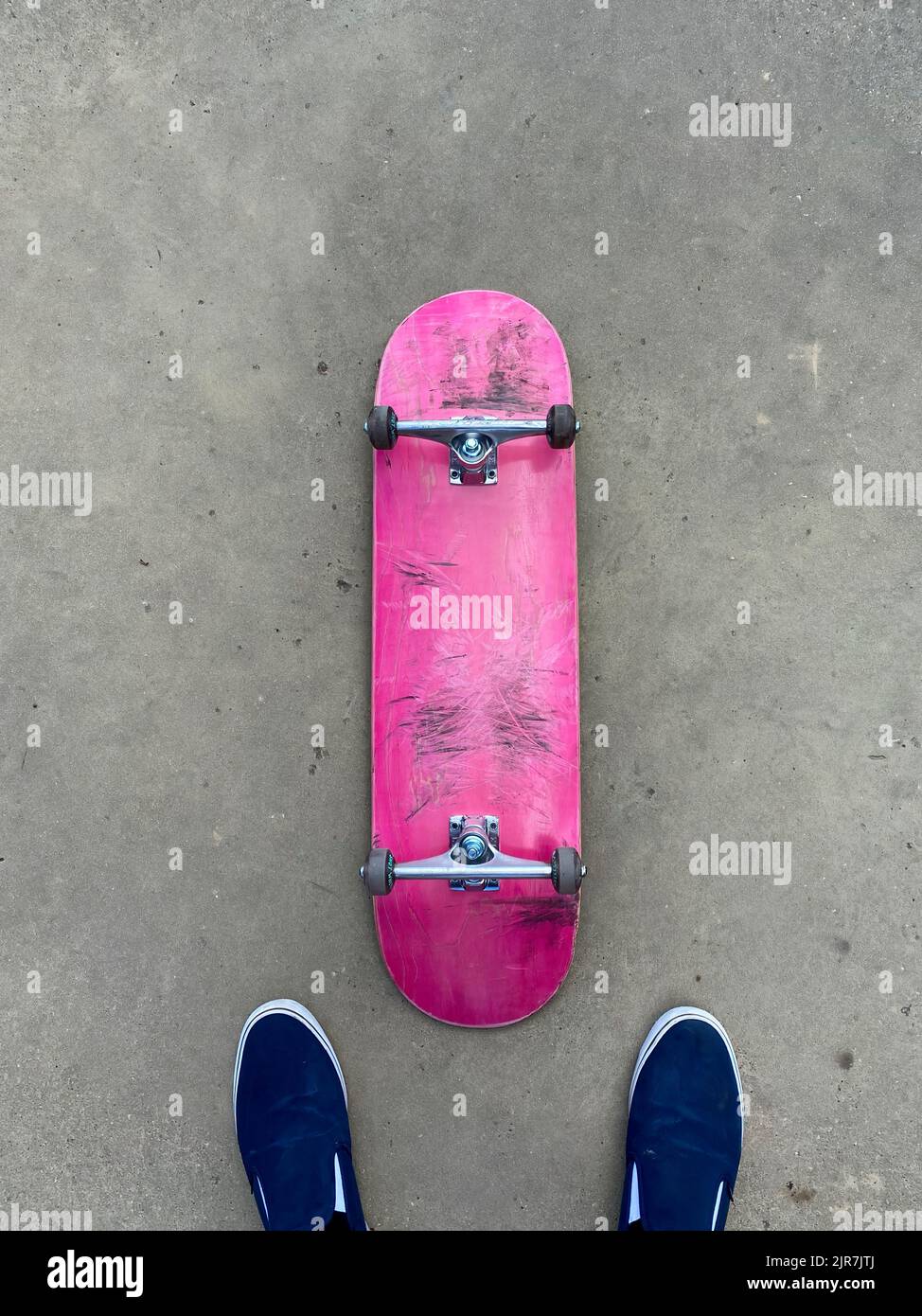 Rosafarbenes Skateboard, das auf einer glatten Betonoberfläche im lokalen Skatepark liegt Stockfoto