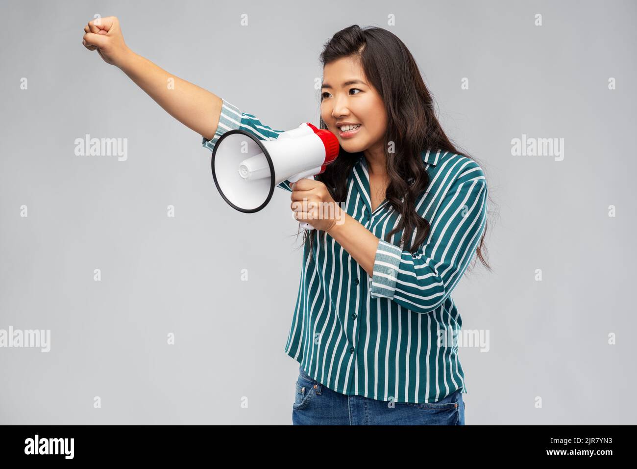 Glücklich lächelnde asiatische Frau, die mit Megaphon spricht Stockfoto