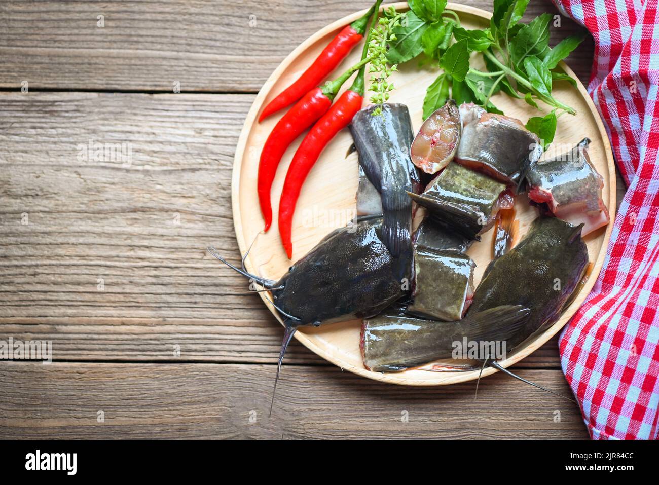 Frische rohe Wels Menü Süßwasserfische, Wels Filet auf Holzplatte, Wels zum Kochen Lebensmittel, Fisch gehackt mit Zutaten Kräuter und Gewürze Stockfoto