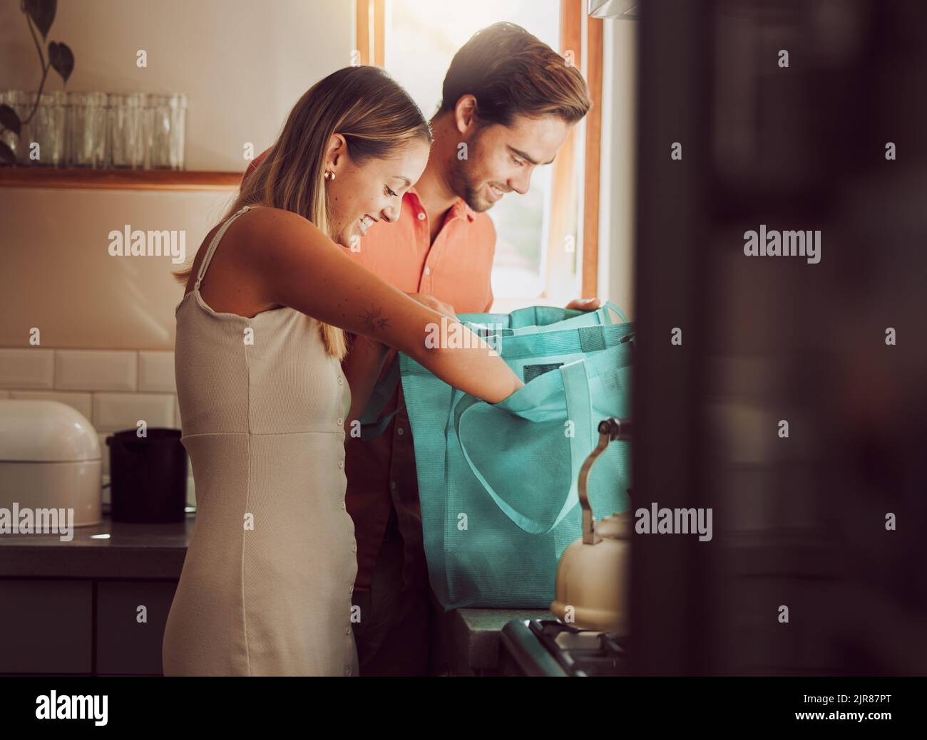 Paar nach dem Einkaufen im Supermarkt nach Hause. Einzelhandel, nachhaltige Einkäufer und junge Menschen Auspacken und Überprüfen von Lebensmitteln Stockfoto