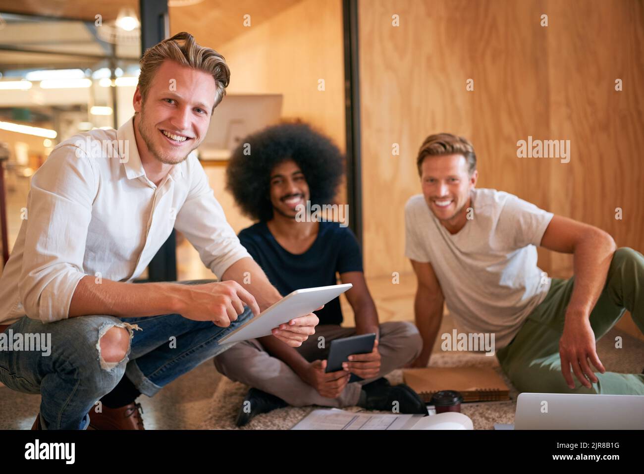 Innovative Ideen in diesem Team kommen uns nicht zu kurz. Porträt eines Teams von Designern, die in einem Büro auf dem Boden Brainstorming. Stockfoto