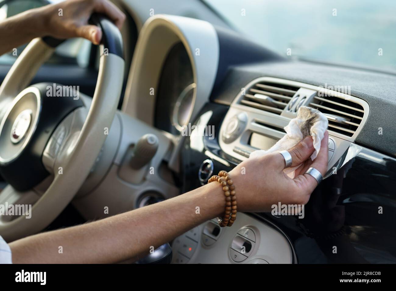 Die Hand des Fahrers wischt Staub von der Lüftungsklappe des Fahrzeugs ab, um den Betrieb des Belüftungssystems zu verbessern Stockfoto