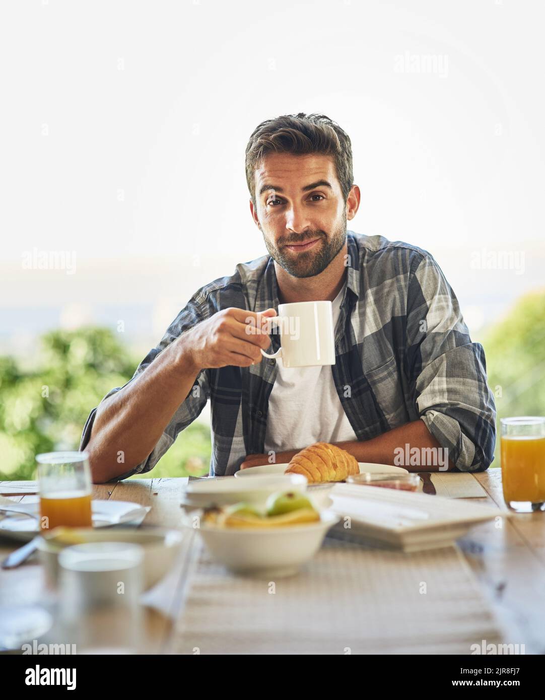 Ich kann den Tag nicht ohne eine starke Tasse Kaffee beginnen. Porträt eines hübschen jungen Mannes, der zu Hause frühstückt. Stockfoto