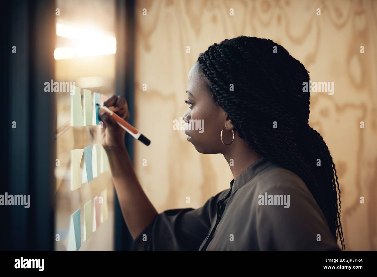 Planung für die Zukunft. Eine junge Designerin schreibt ihre Ideen auf Haftnotizen. Stockfoto