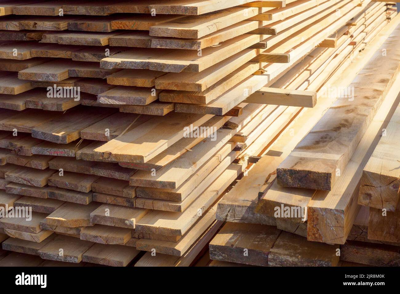 Holzbretter werden in einem Sägewerk oder einer Schreinerei gestapelt. Sägen Trocknen und Vermarktung von Holz. Industrieller Hintergrund Stockfoto