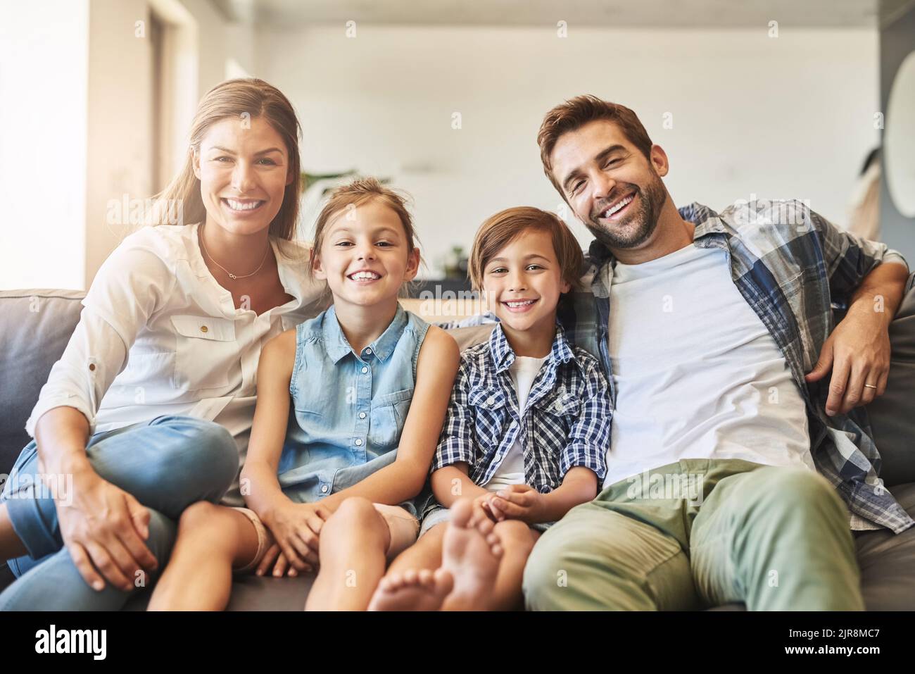 Die beste Zeit für die Familie. Eine glückliche vierköpfige Familie, die sich zu Hause auf dem Sofa entspannt. Stockfoto