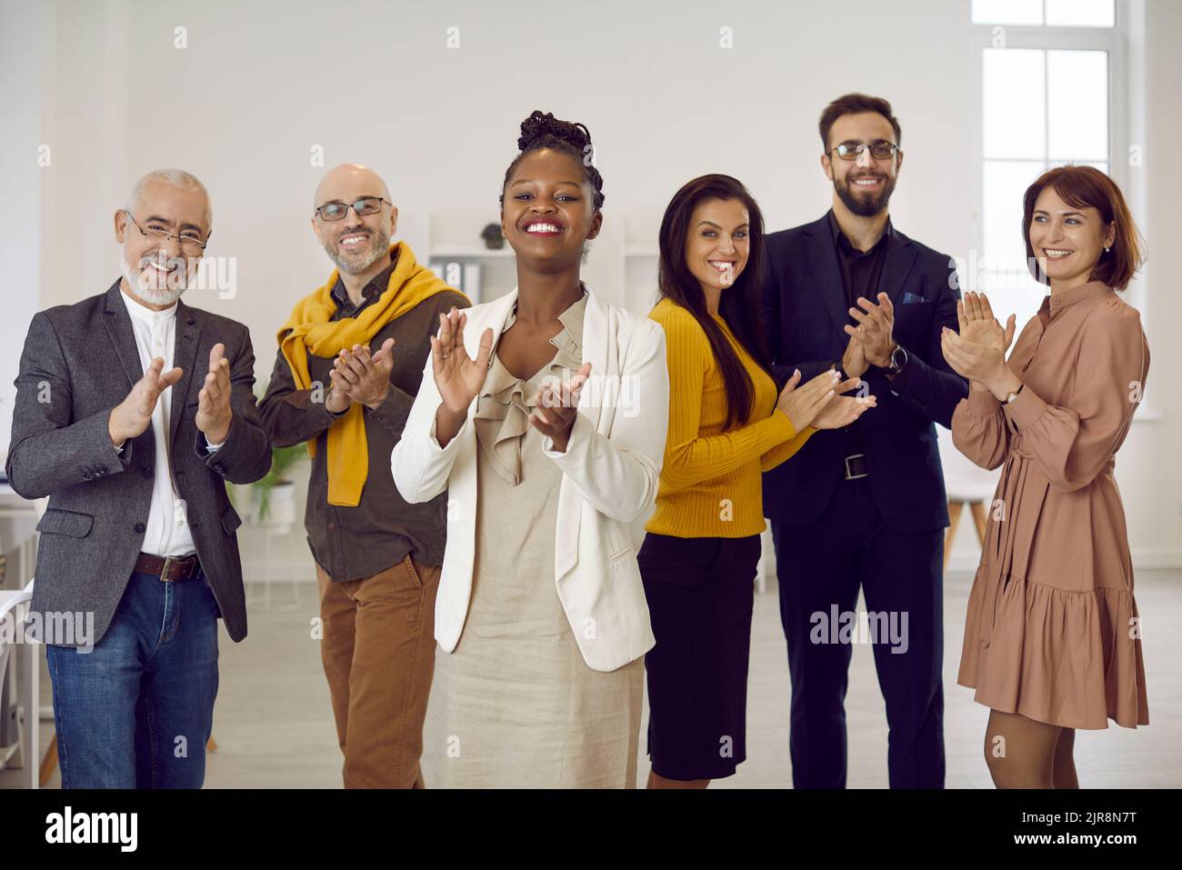 Porträt einer Gruppe von multiethnischen Geschäftsleuten, die applaudieren und stolz lächeln und die Kamera betrachten. Stockfoto