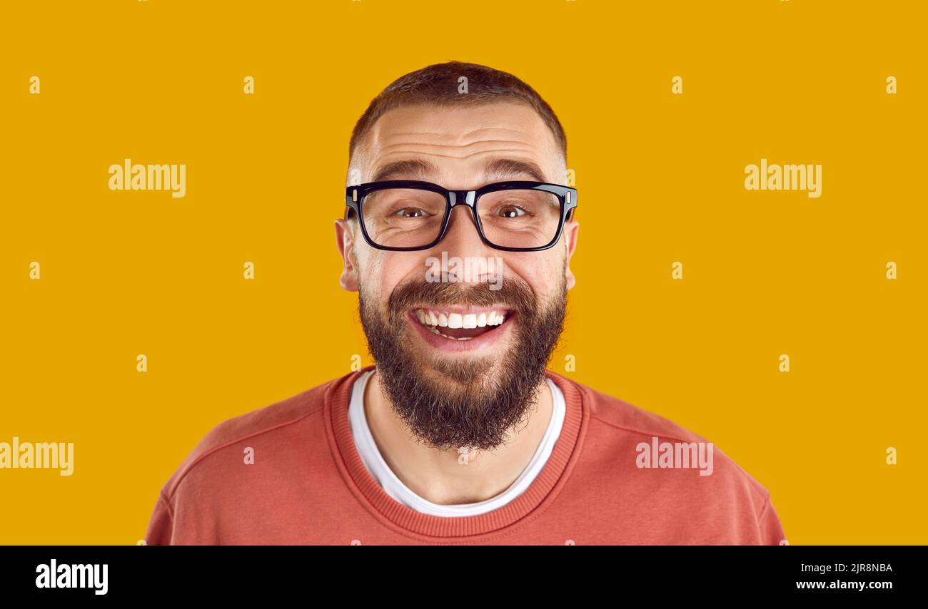 Kopfschuss eines fröhlichen, lustigen bärtigen Mannes in einer Brille, der lächelnd und lachend auf die Kamera schaute Stockfoto