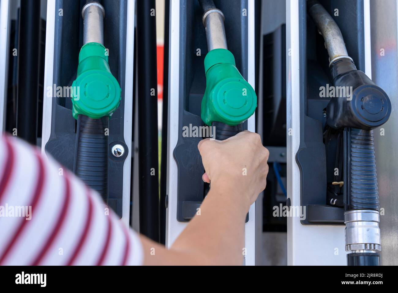 Die Hand einer Frau entfernt eine Tankpistole aus der Pumpe, um das Auto aufzutanken Stockfoto