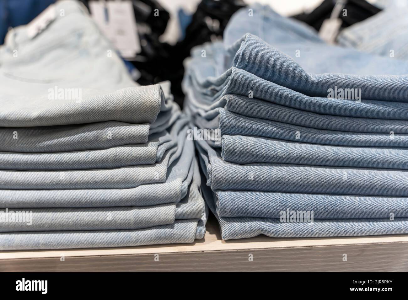 Ein Stapel von blauen Jeans auf einem Regal im Laden. Mode Bekleidungsgeschäft Stockfoto