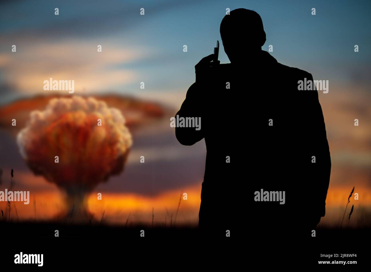 Das Konzept eines Atomstreiks. Silhouette eines Mannes, der am Telefon anruft und den Befehl zum Explodieren gibt. Ein Politiker, der einen Atomkrieg begann Stockfoto