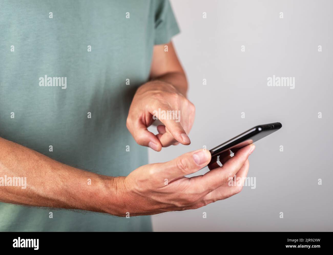 Mann Zeigefinger berühren Smartphone-Bildschirm zum Tippen. Männlicher Klick auf OK-Taste. Telefonieren im modernen Leben. Hochwertige Fotos Stockfoto