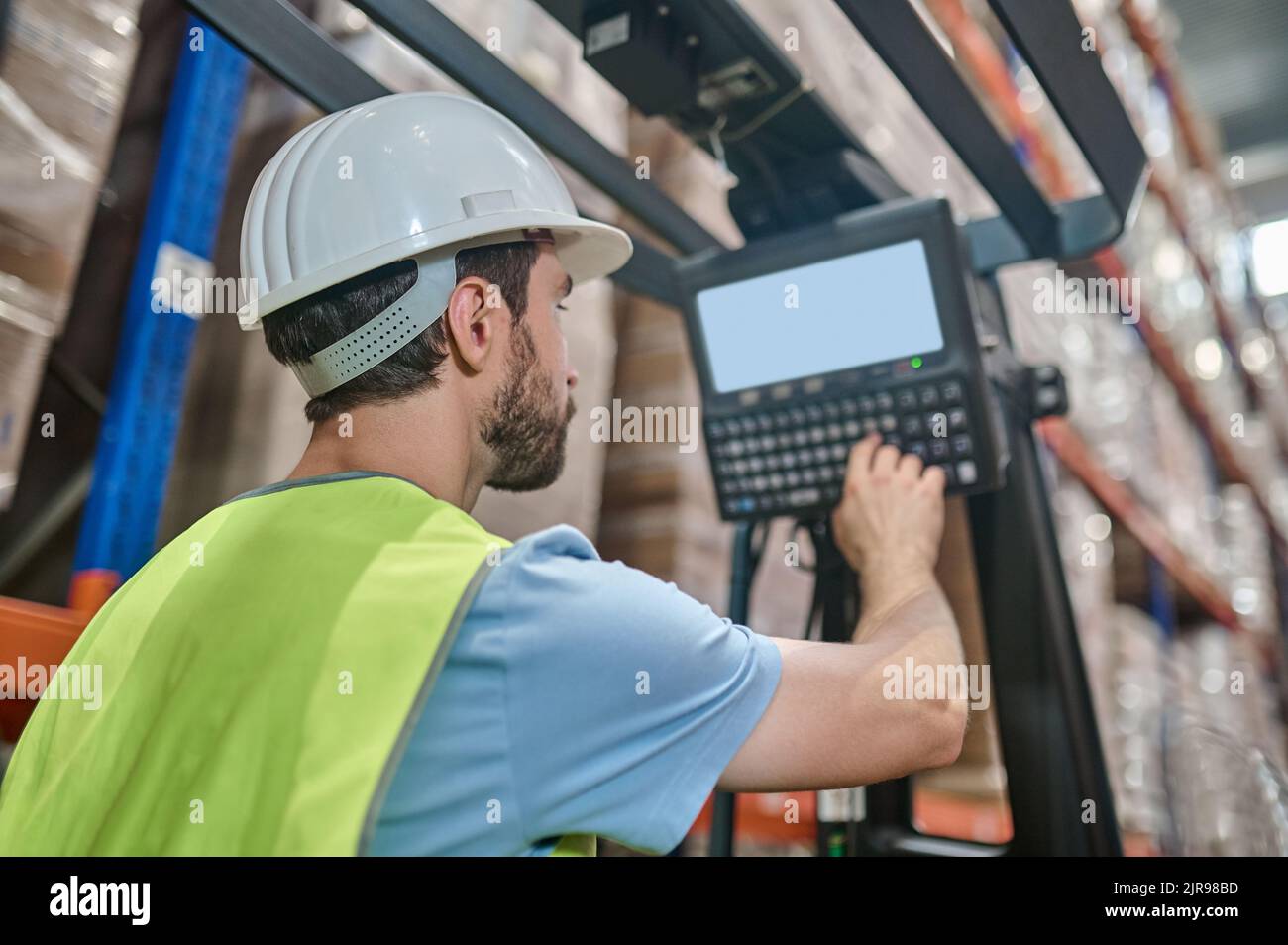 Erfahrener Lagermitarbeiter, der den Elektrohubwagen betreibt Stockfoto