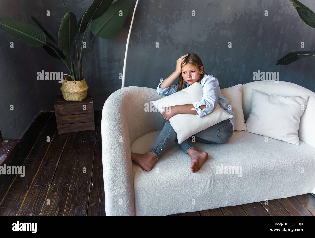 Porträt einer schönen jungen Frau mit einem depressiven Ausdruck auf einem Sofa sitzend. Traurige Frau in ihrem Zimmer. Hochwertige Fotos Stockfoto