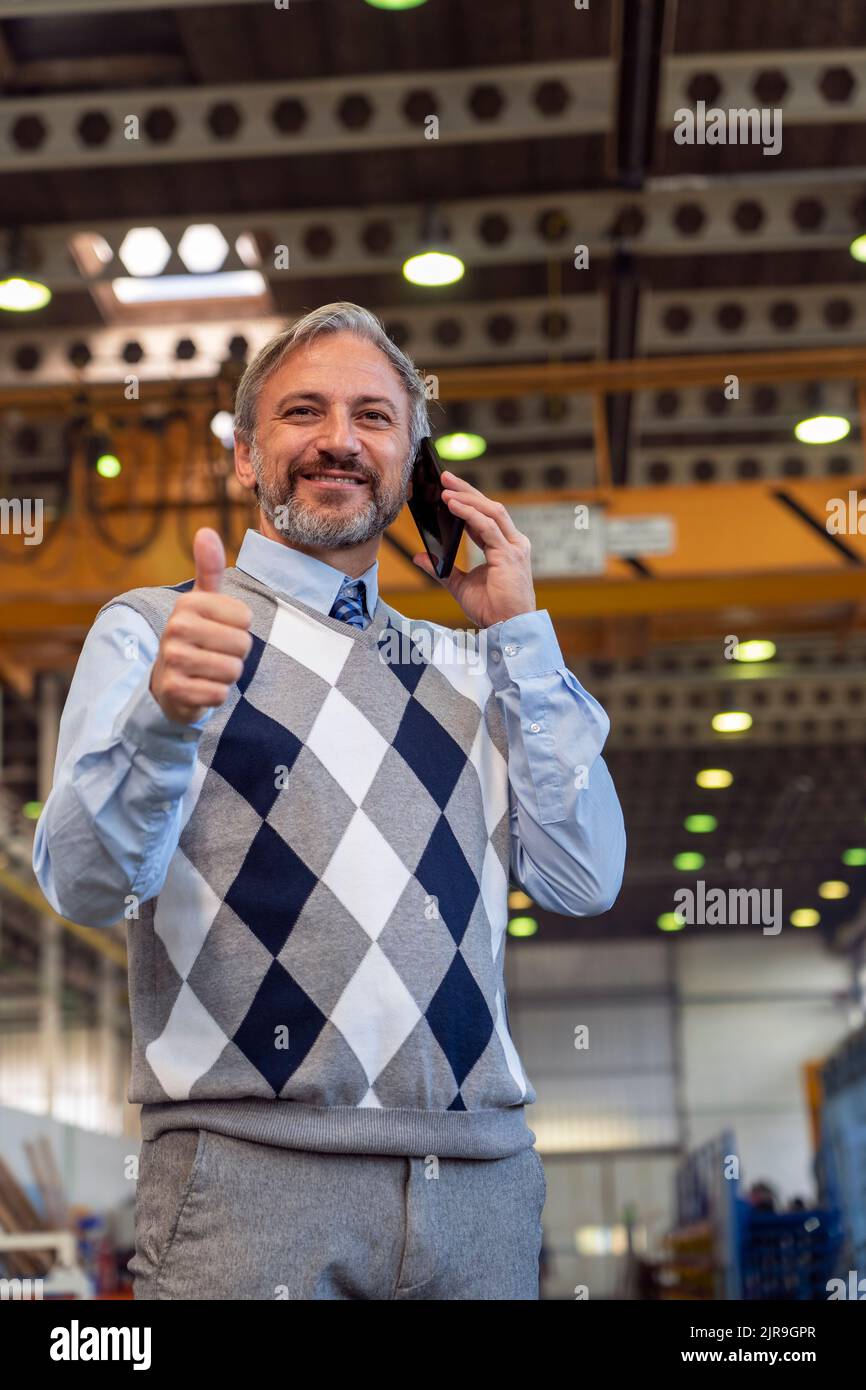 Taille Nach Oben Porträt Eines Selbstbewussten, Hübschen, Grauhaarigen Geschäftsmanns Oder Ingenieurs Im Industriellen Innenausbau. Charismatischer Mann Steht Und Benutzt Handy In Stockfoto