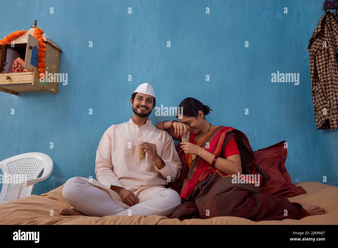 Maharashtrian Paar Tee, während auf Kinderbett zu Hause sitzen Stockfoto