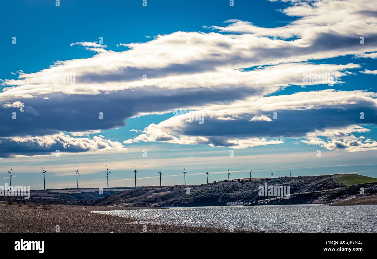 -Landschaft von Windmühlen im Hintergrund neben dem Ricobayo-Stausee in Montamarta (Zamora - Spanien) an einem Tag mit vielen Wolken Stockfoto